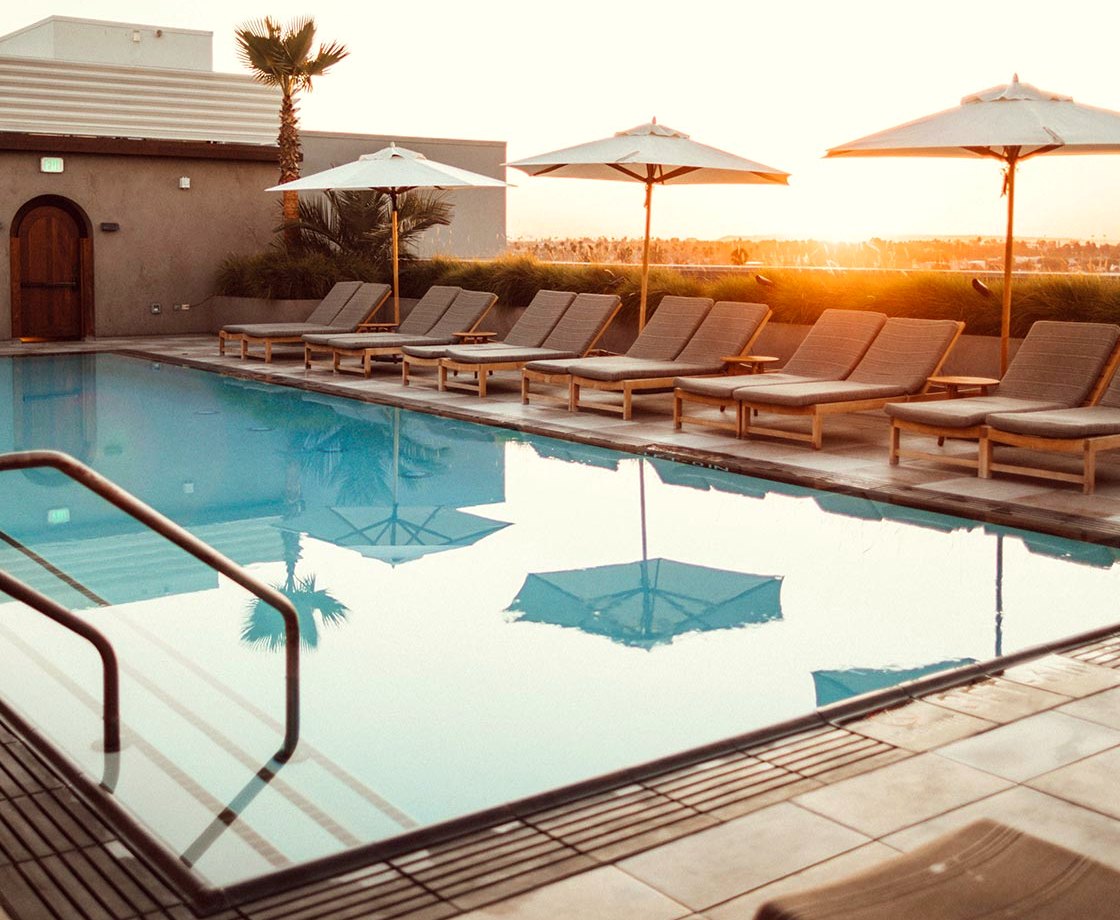 A long pool at evening with loungers and umbrellas along one side