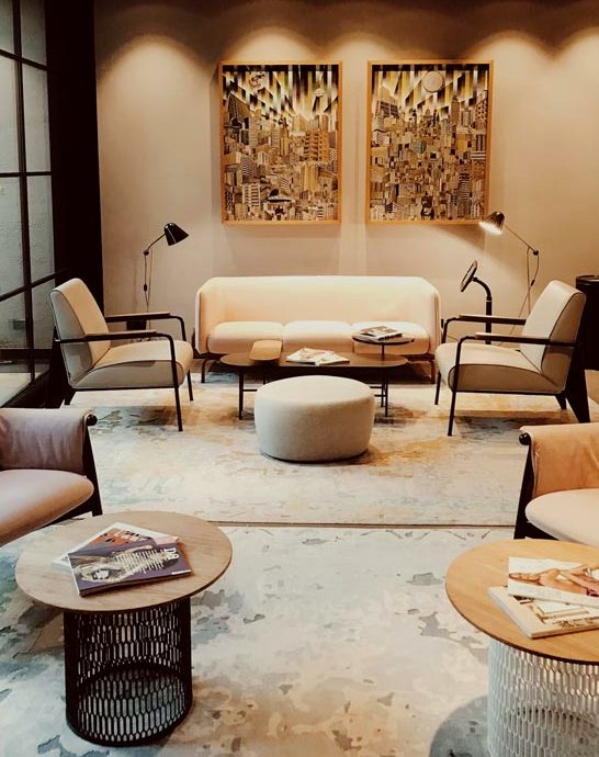 A lounge with woven panels, low chairs and lamps